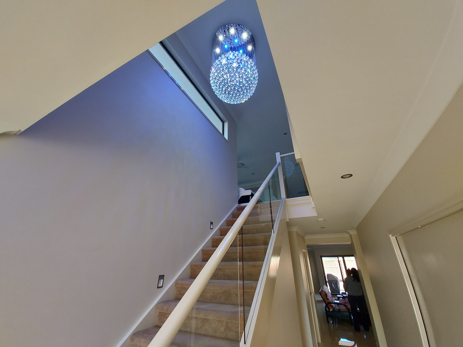 Crystal chandelier lighting a stairwell with a glass balustrade
