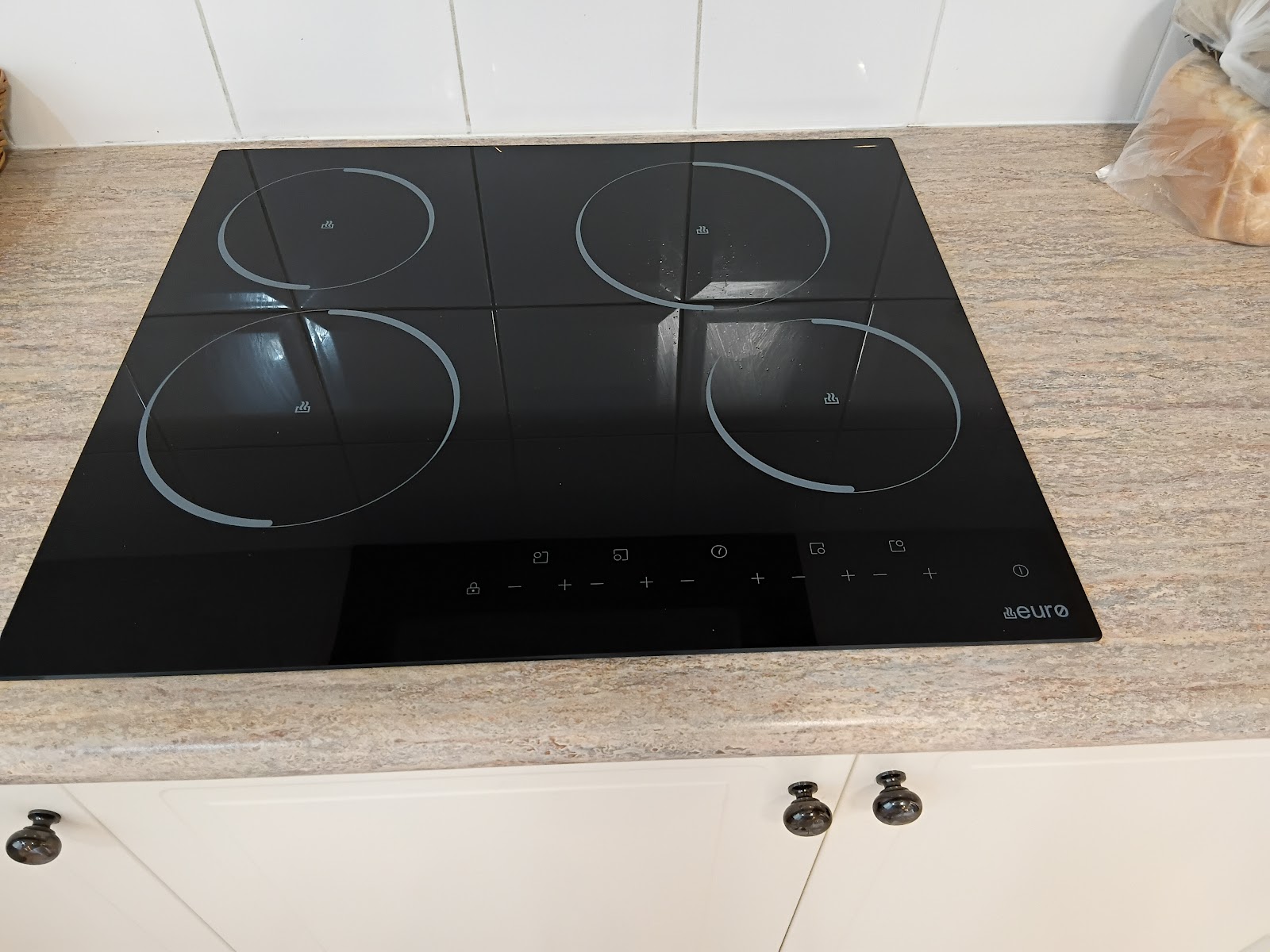 Black induction cooktop installed in a stone benchtop